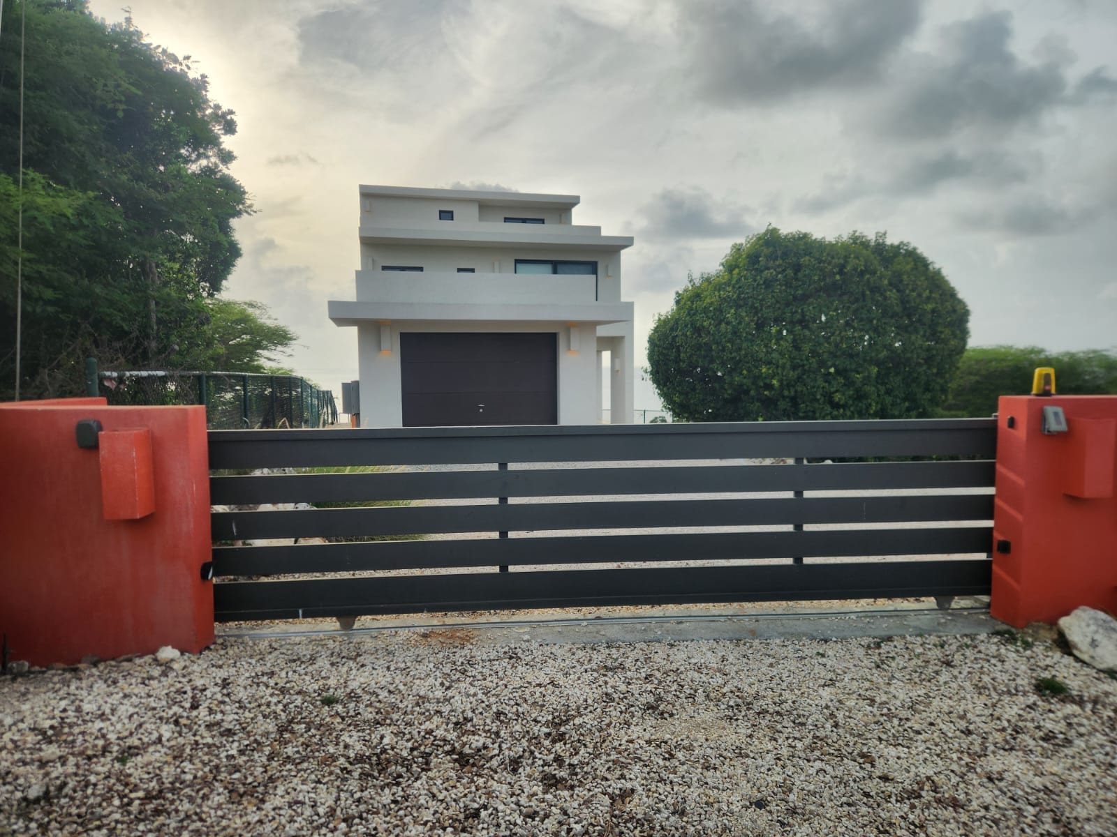 Dark grey aluminium slat sliding gate at the driveway of a modern villa in Anguilla