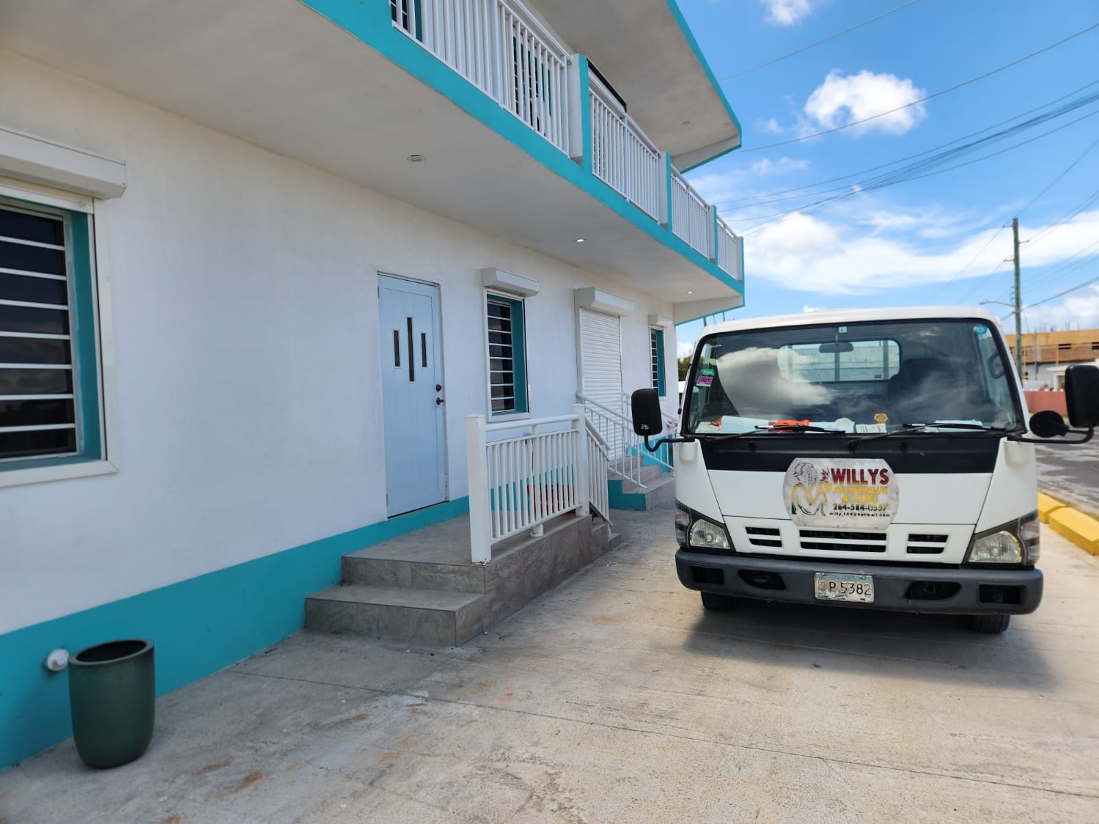 The Willy's Aluminium and Steel truck outside a finished apartment building with aluminium railings, roller shutters and louvre windows in Anguilla