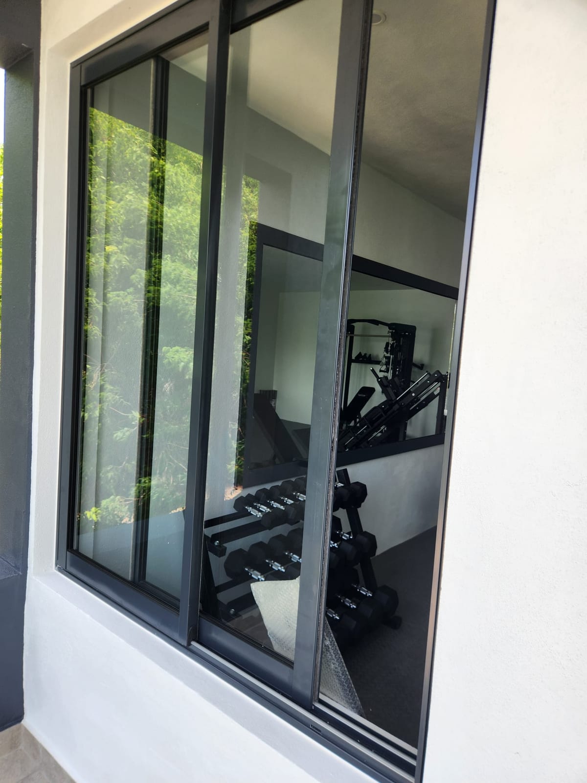 Black framed aluminium sliding window looking into a home gym in Anguilla