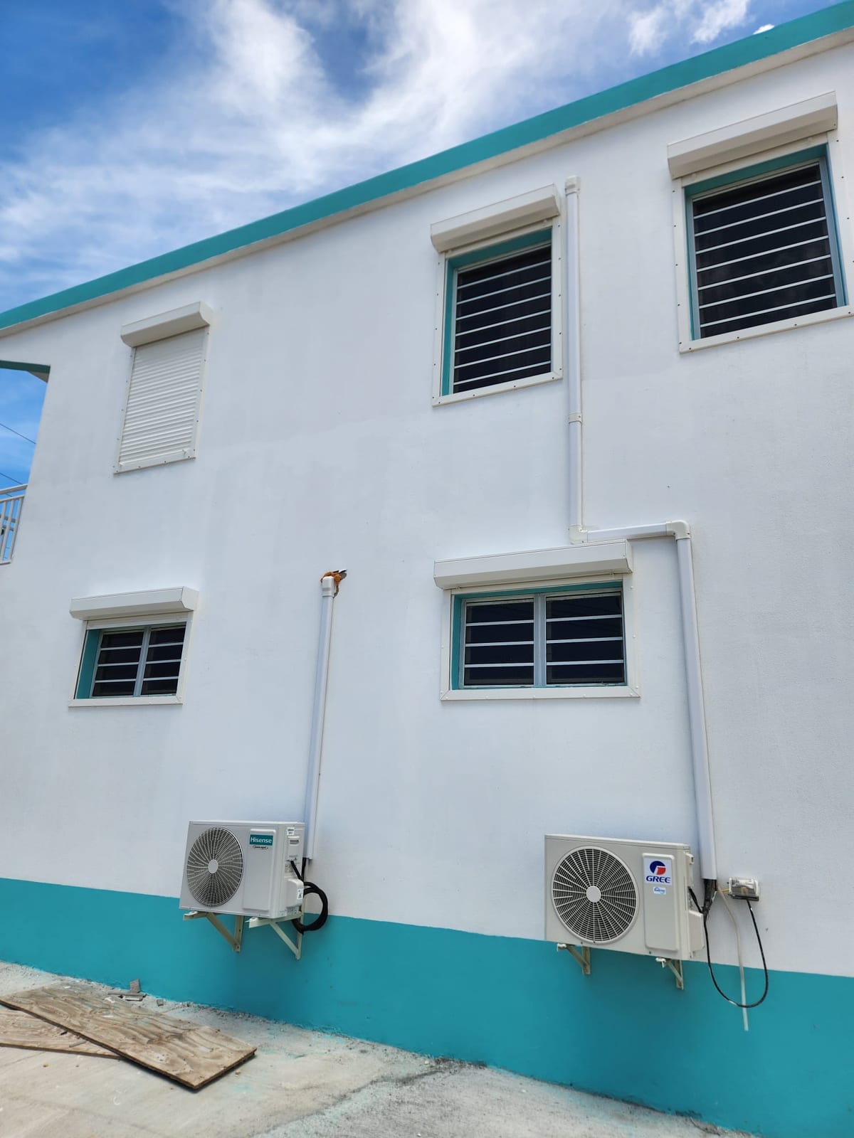 White louvre windows and roller shutters across the side elevation of an apartment building in Anguilla