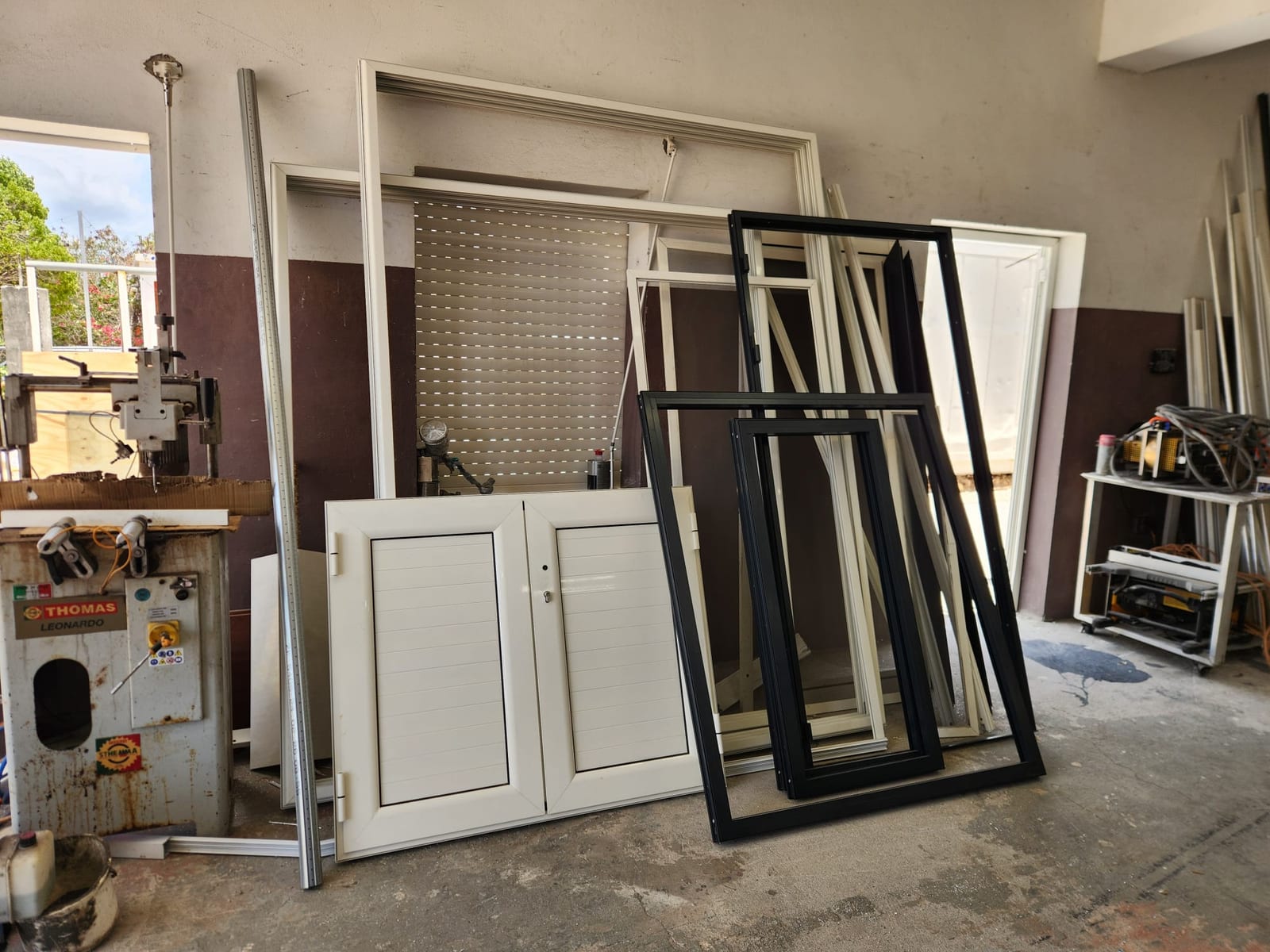 Aluminium door and window frames stacked beside fabrication machinery in the Anguilla workshop